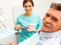 An older man smiling at the camera alongside a dentist