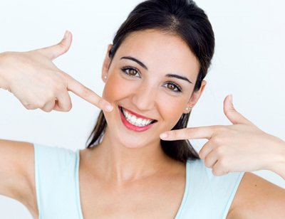 young woman pointing to her white smile  