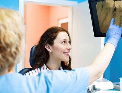 A dentist pointing at an X-ray with a patient.