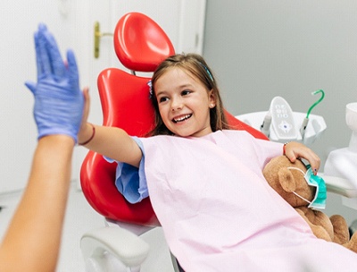 A young girl gives her dentist in Toledo a high-five after a successful checkup and cleaning