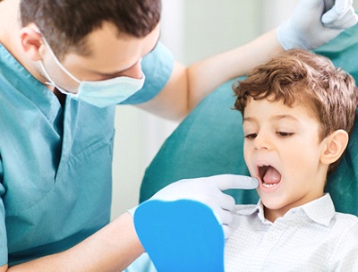 A dentist shows a young boy his smile after completing a dental checkup
