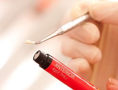 A dentist extracting a small bit of composite resin from its tube