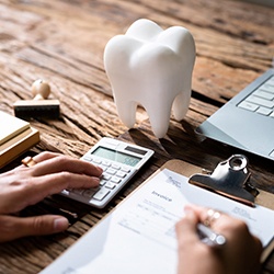 Someone filling out paperwork with a tooth on their desk