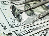 Cost of dentures in Toledo represented by money bills and dental tools