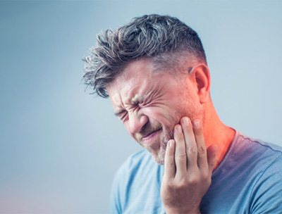 man holding the side of his cheek in pain