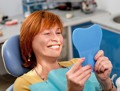 A middle-aged woman with red hair is smiling after receiving her dental implants post-op instructions in Toledo