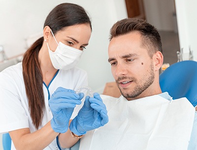 Invisalign dentist in Toledo showing clear aligner to patient