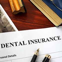 Dental insurance paperwork on brown wooden desk