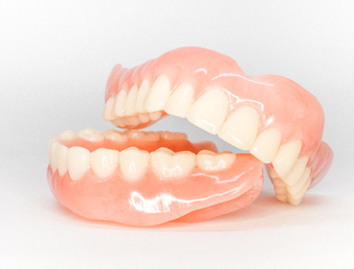 Complete set of shiny dentures on white surface