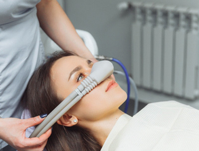 Woman’s hands placing nitrous oxide mask over patient’s nose