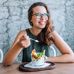 Woman smiling while eating healthy meal at home