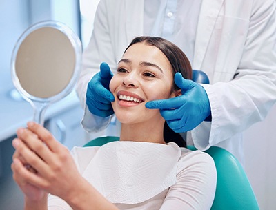 Woman smiling at reflection in handheld mirror