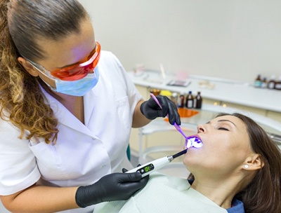 A female patient who is sedated while a dentist examines her mouth