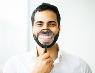 man using magnifying glass to show off results of teeth whitening in Toledo  