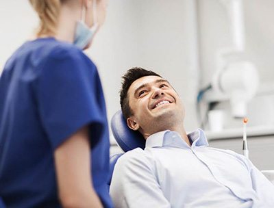 Dentist explaining cost of cosmetic dentistry in Toledo to smiling patient