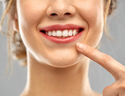 close up of woman pointing to her white smile 