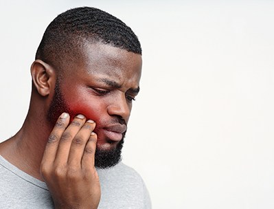Close-up of man in grey shirt with jaw pain