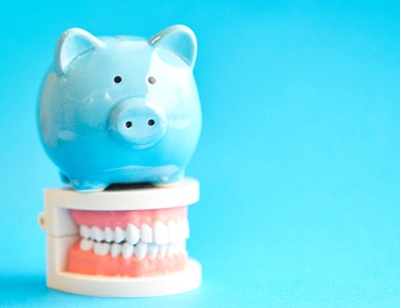 Piggy bank atop model teeth represent cost of veneers in Toledo