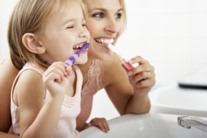 Family brushing teeth side-by-side