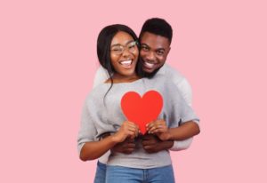 young couple in gray sweaters holding love heart