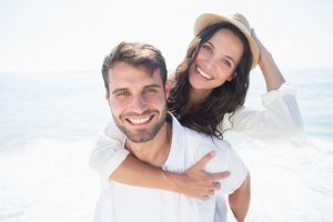 couple smiling on the beach after visiting their cosmetic dentist 