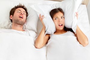 Man snoring next to woman in bed