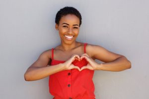 a woman smiling and using her hands to form a heart