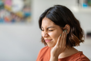 Woman wincing and rubbing her ear