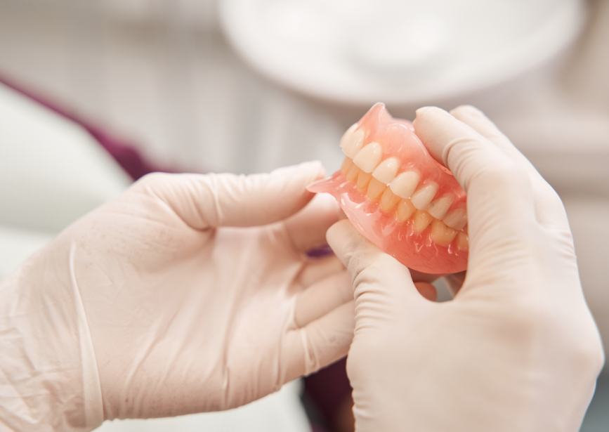 Gloved hands holding dentures